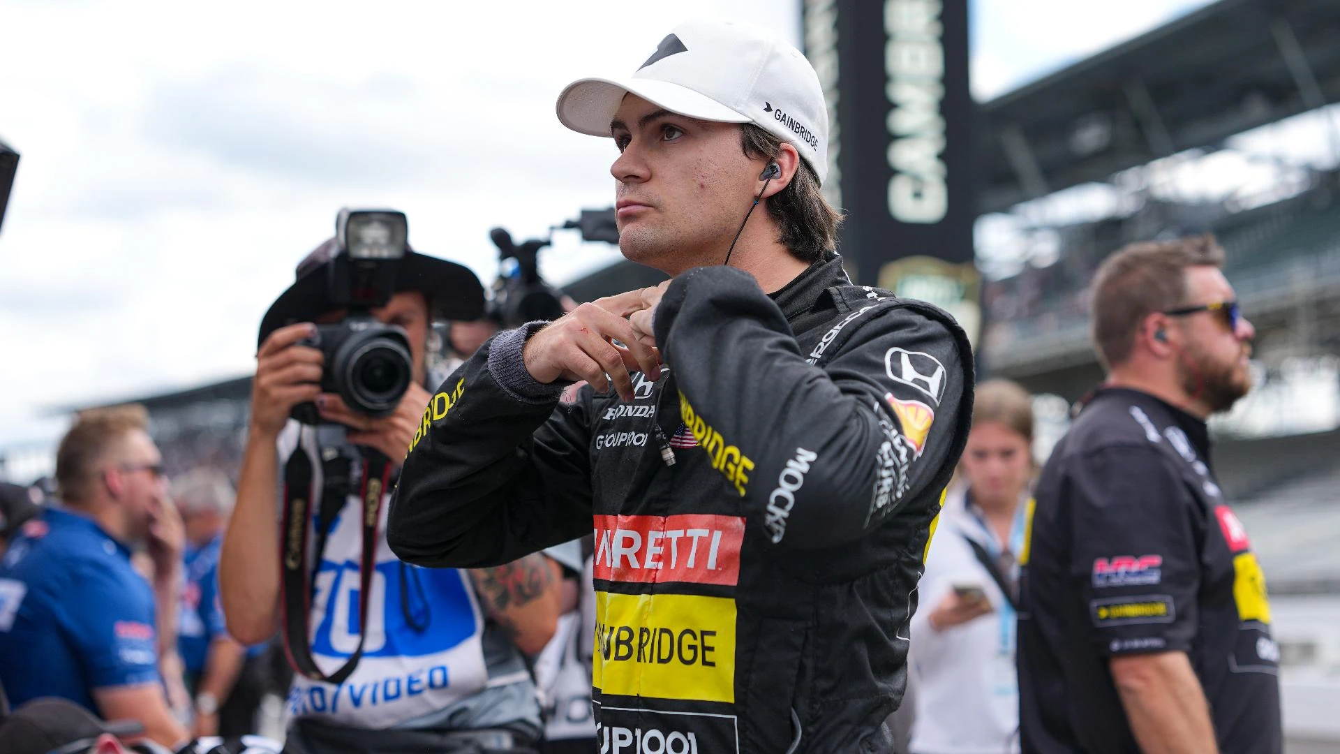 Colton Herta fokus mempersiapkan diri sebelum balapan, mengenakan balutan racing suit hitam dan topi putih 
