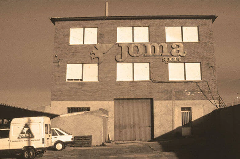 Gedung pabrik Joma Sport lama dengan logo besar di dinding 