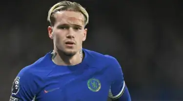 Mykhailo Mudryk berlatih di Cobham, tatapannya fokus; latar tribun agak kabur.