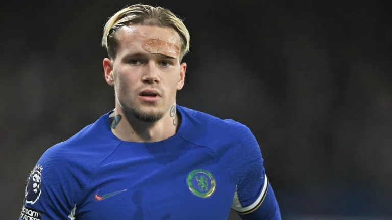 Mykhailo Mudryk berlatih di Cobham, tatapannya fokus; latar tribun agak kabur.